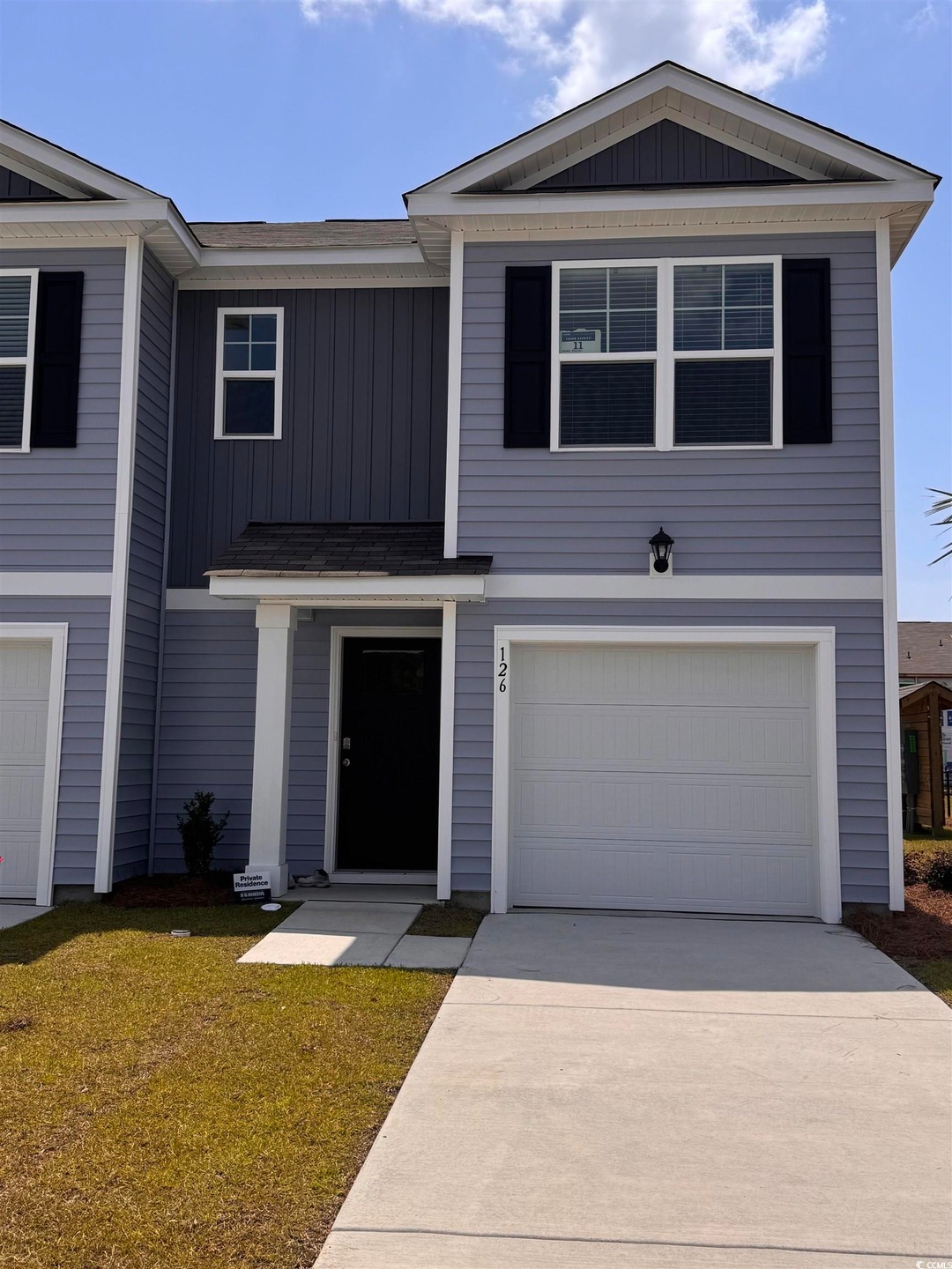 View of front facade with board and batten siding, an attached garage, concrete driveway, and a front yard