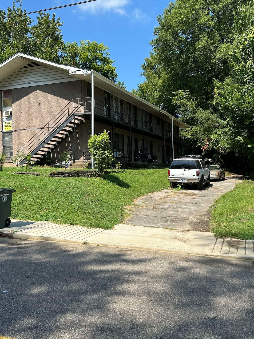 View of front facade with stairs, a front lawn, and driveway