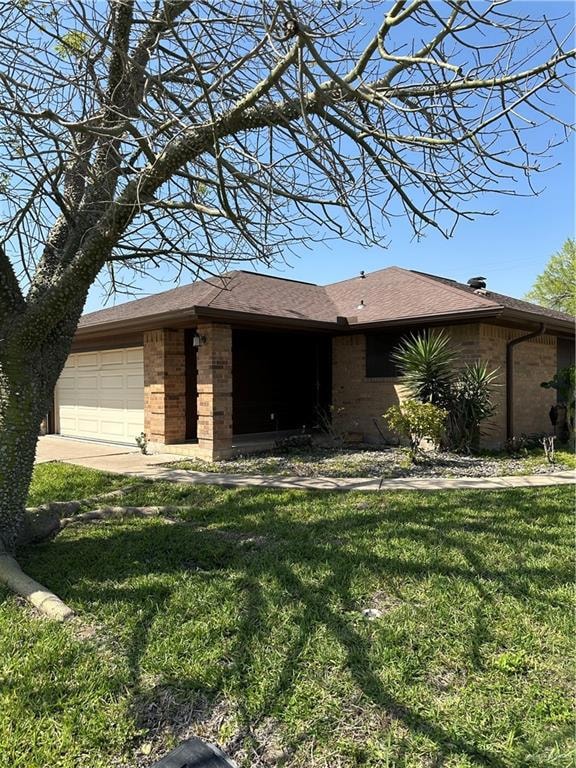 View of front of property featuring brick siding, an attached garage, a front lawn, and covered entrance.