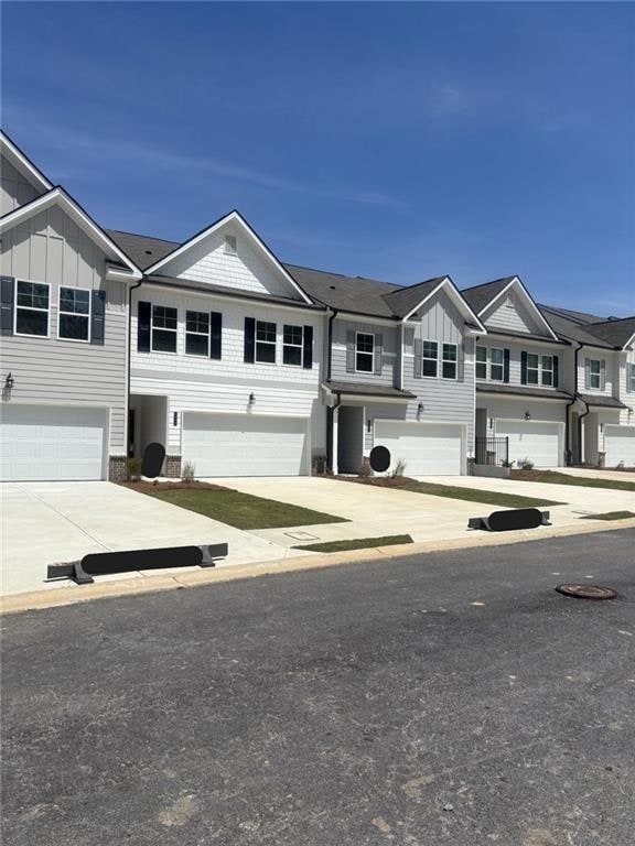 View of front of property featuring board and batten siding, driveway, a residential view, and brick siding