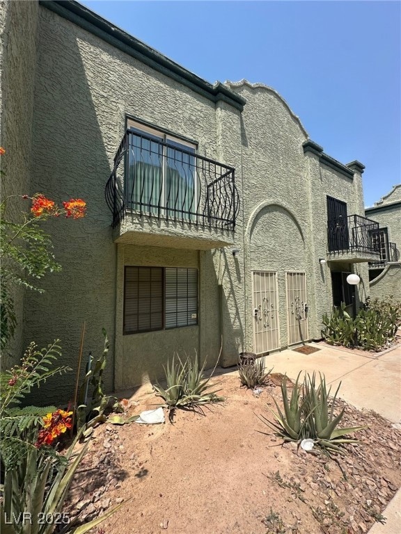 View of front of home with a balcony and stucco si