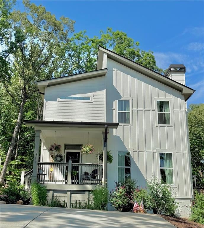View of front of house featuring a porch, board and batten siding, and a chimney
