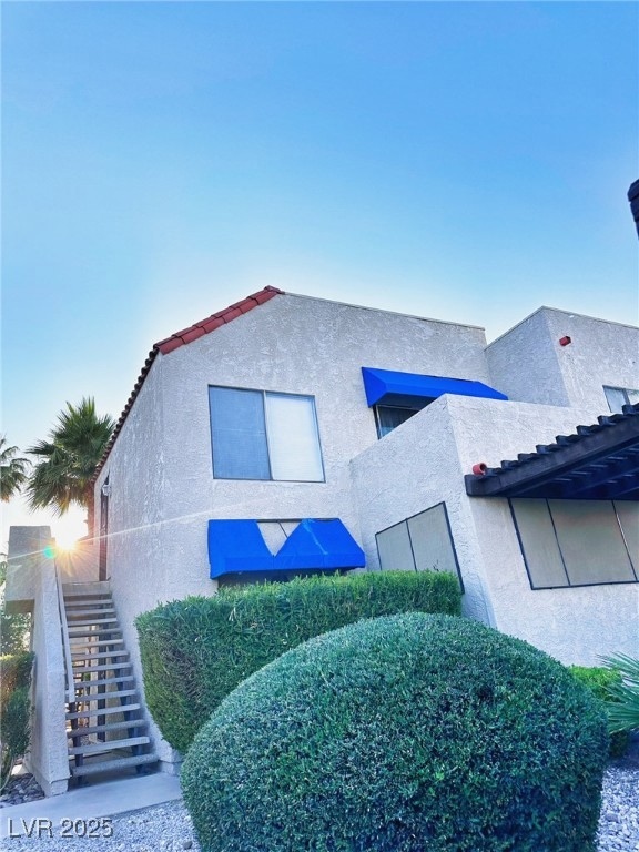 View of property exterior with stairway and stucco