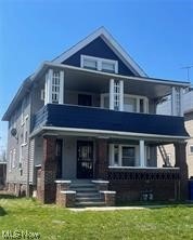 View of front of property featuring a front yard and a balcony