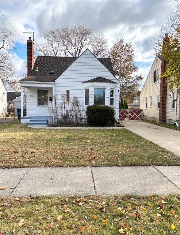 Bungalow-style home with a chimney, a front lawn, and a shingled roof