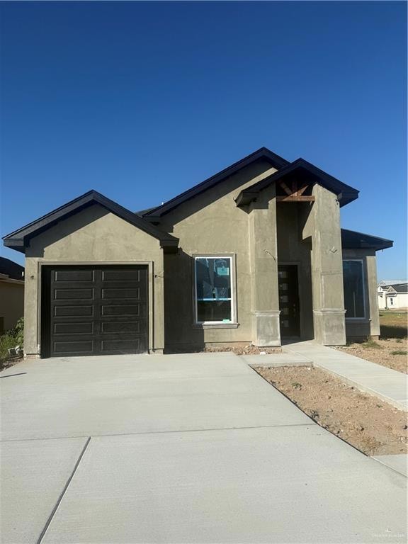 View of front of home featuring driveway, a garage, and stucco siding