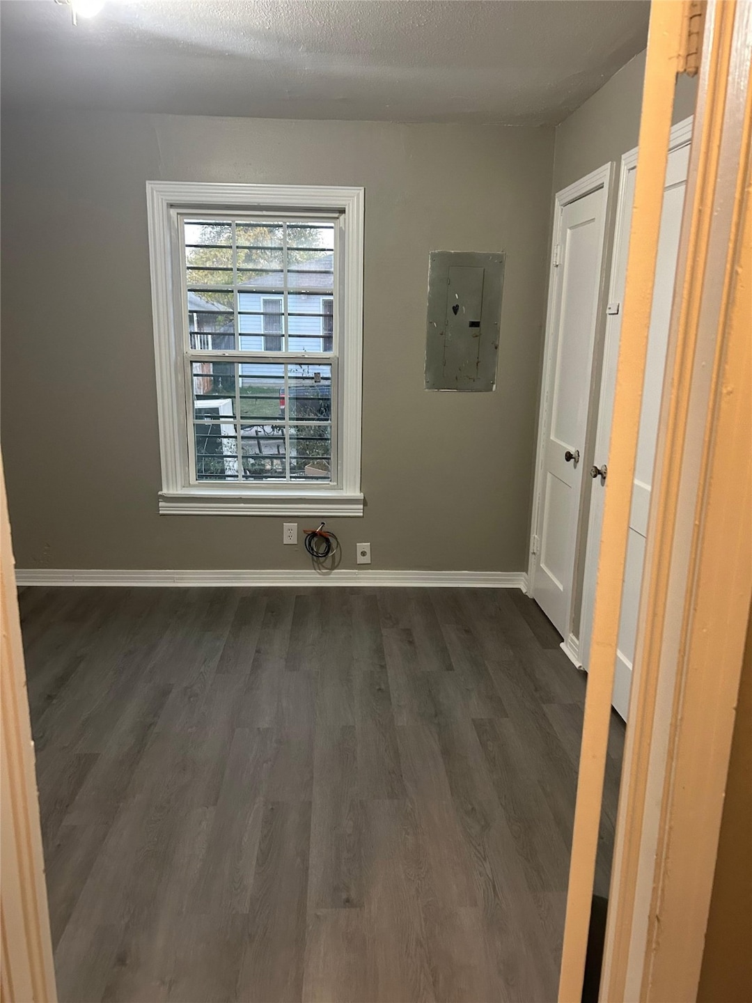 Spare room featuring dark wood-style flooring, electric panel, and a textured ceiling