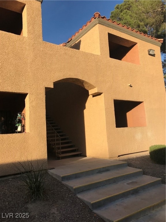 Doorway to property with a tile roof and stucco si