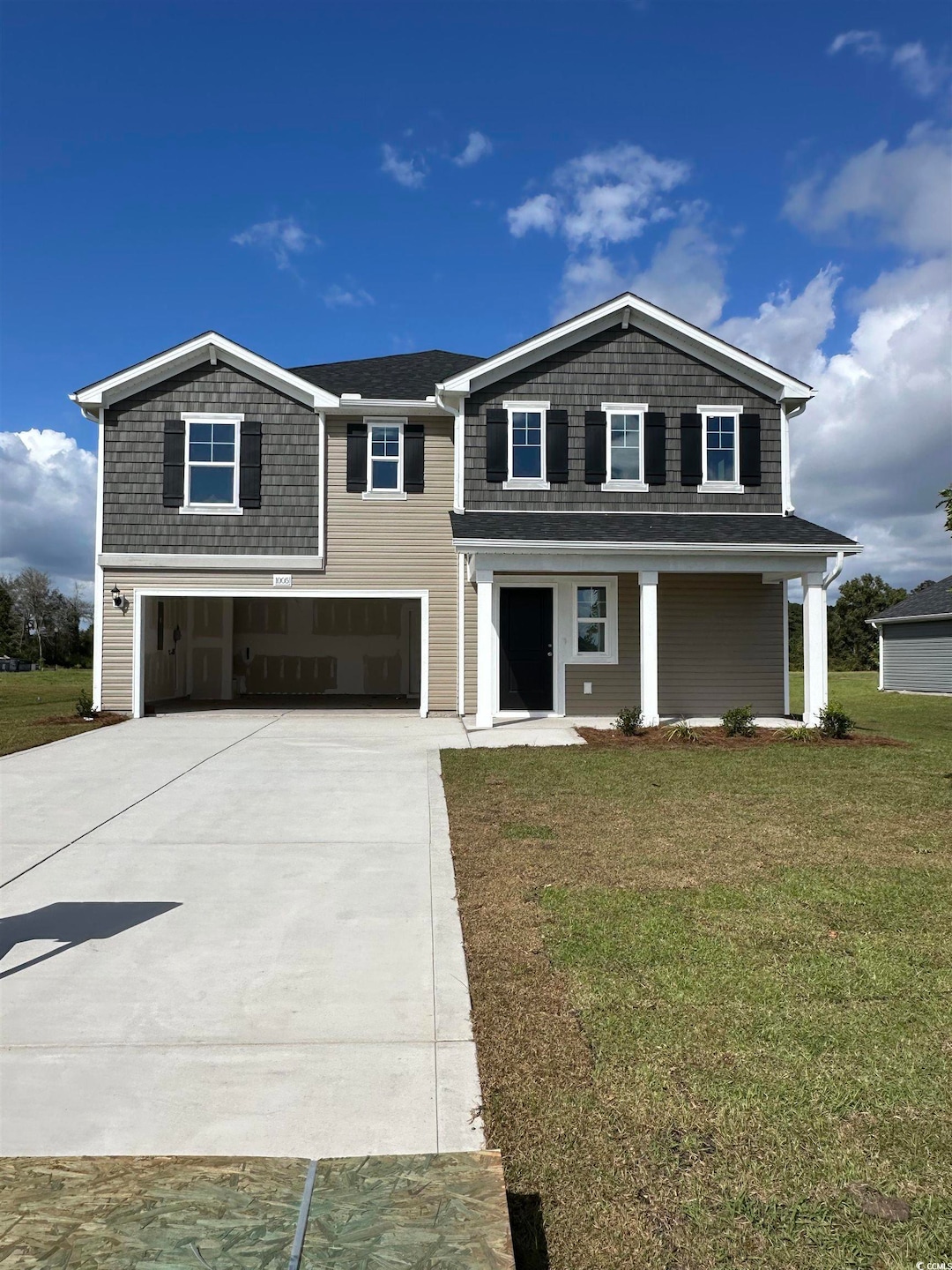 View of front facade with concrete driveway, a front yard, a garage, and a porch