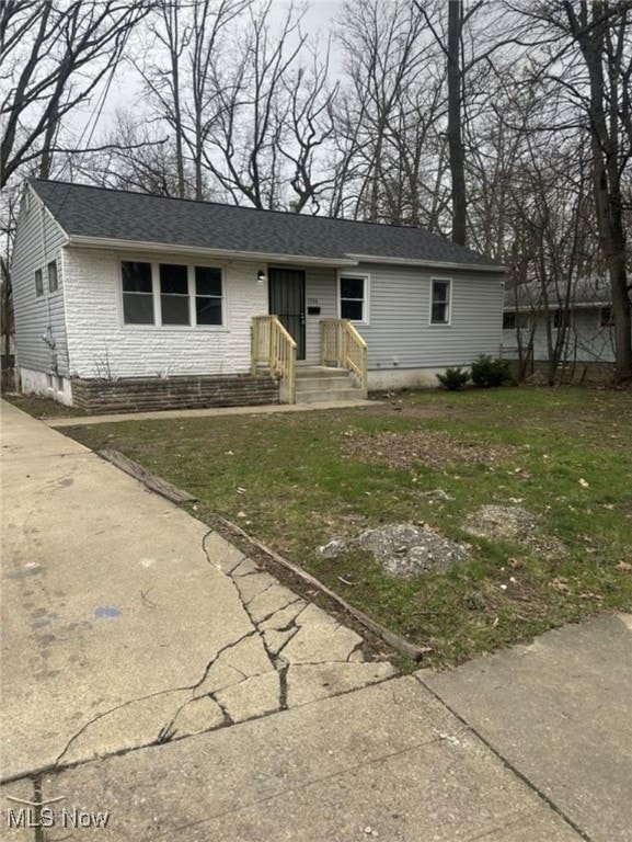 Ranch-style home with brick siding, roof with shingles, and a front lawn
