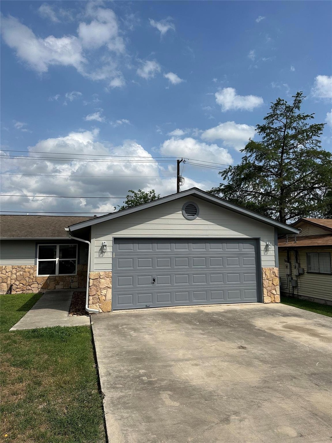 Ranch-style house with concrete driveway, stone s