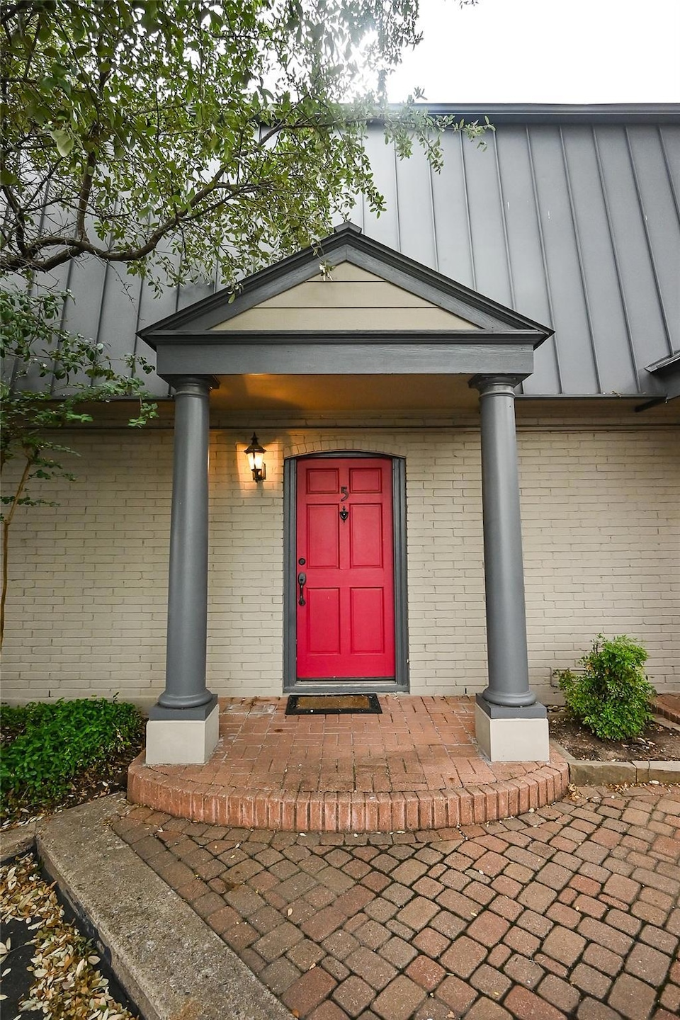Doorway to property featuring covered porch, bric