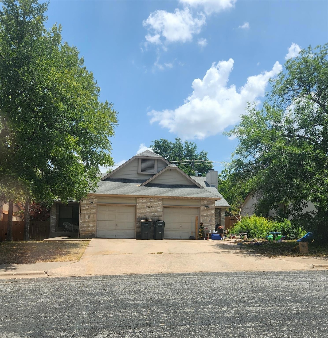 View of front of house featuring driveway, brick siding, and a shingled roof