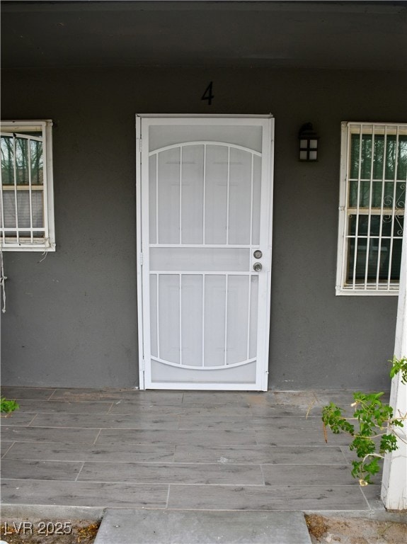 Property entrance featuring stucco siding and a po