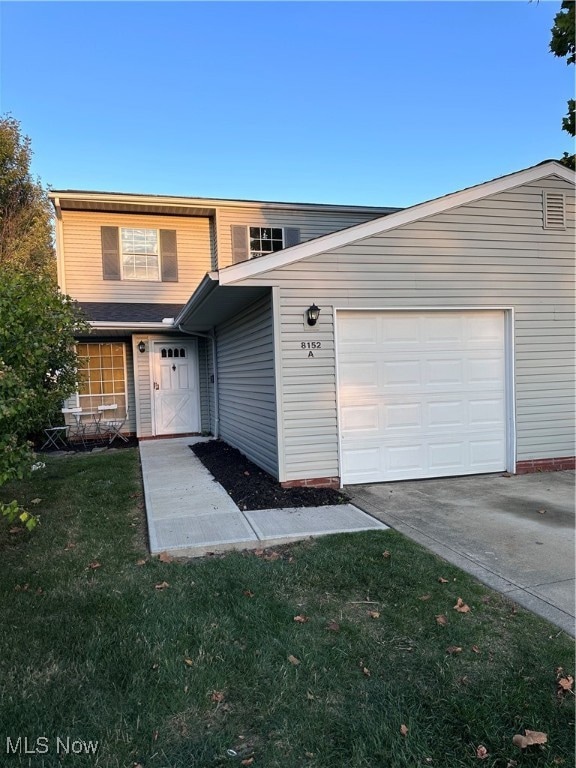 Traditional-style house with driveway, a front lawn, and an attached garage