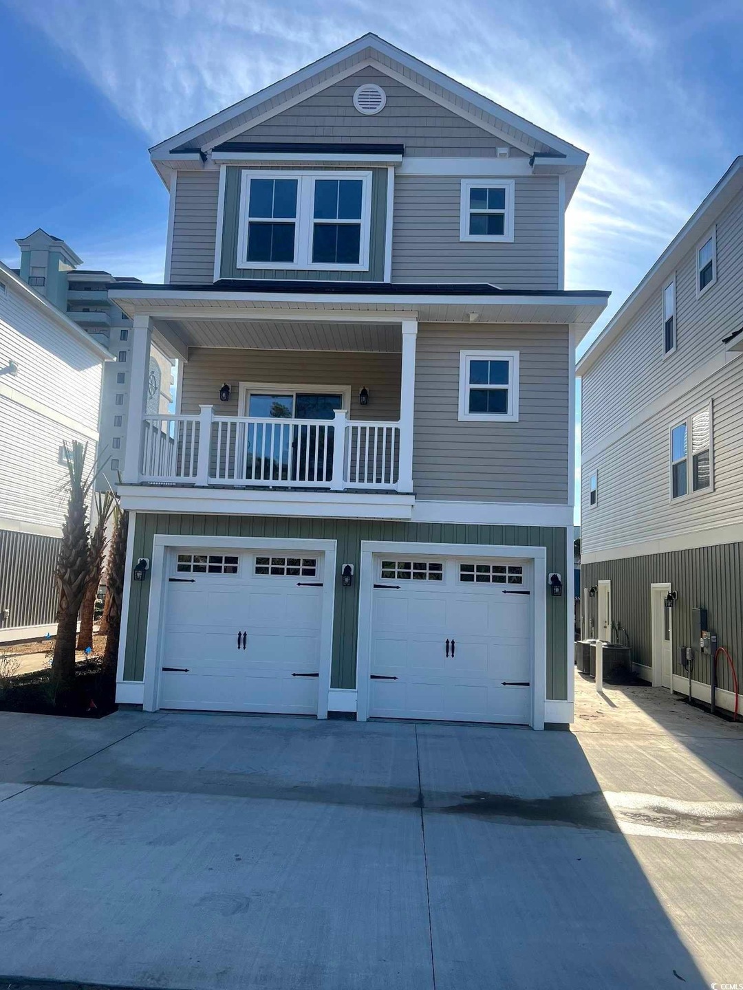 View of front of home featuring driveway, an attached garage, and a balcony