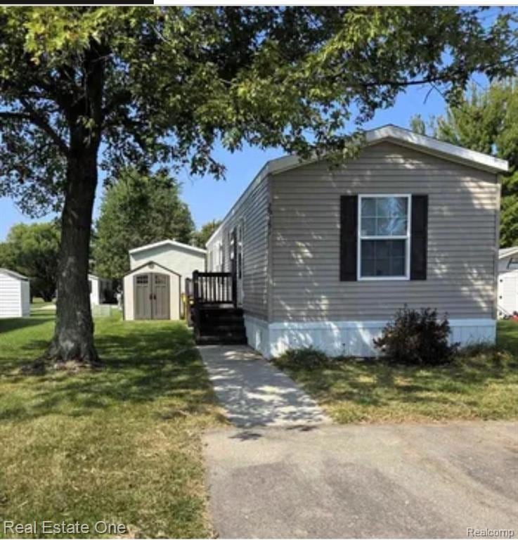 View of side of home with a shed and a yard