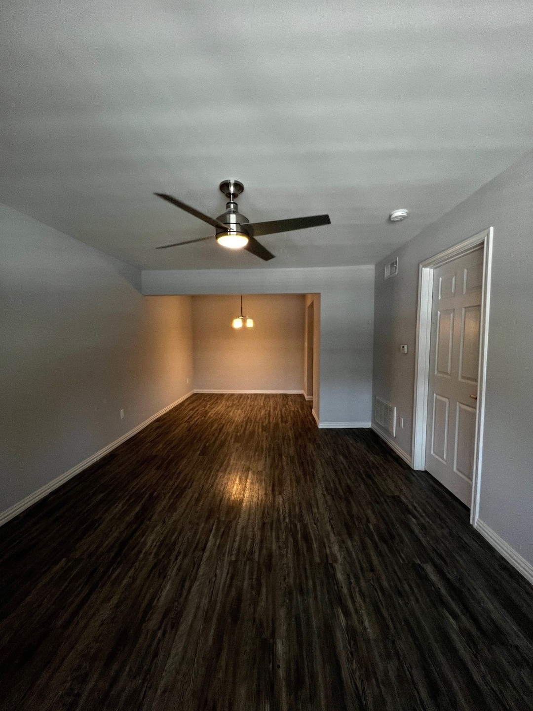 Empty room with dark wood-style flooring and a ceiling fan