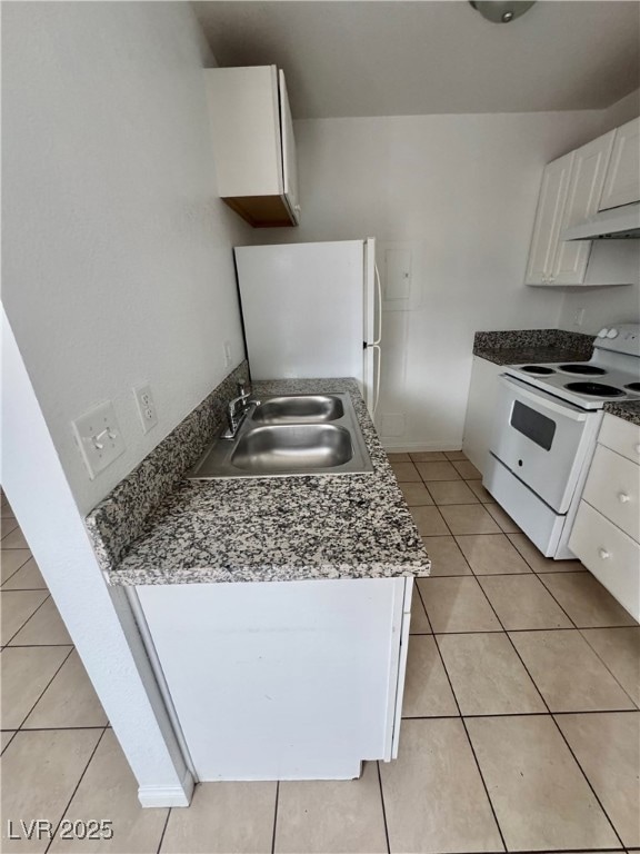 Kitchen featuring white cabinets, white appliances, light tile patterned flooring, under cabinet range hood, and dark countertops
