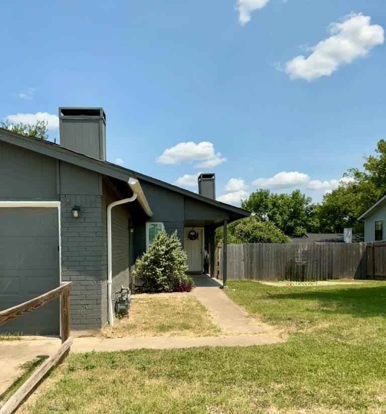 View of side of property with a chimney, brick siding, and an attached garage
