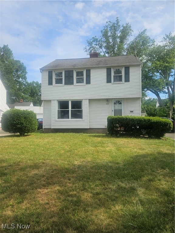 Colonial house featuring a front lawn and a chimney
