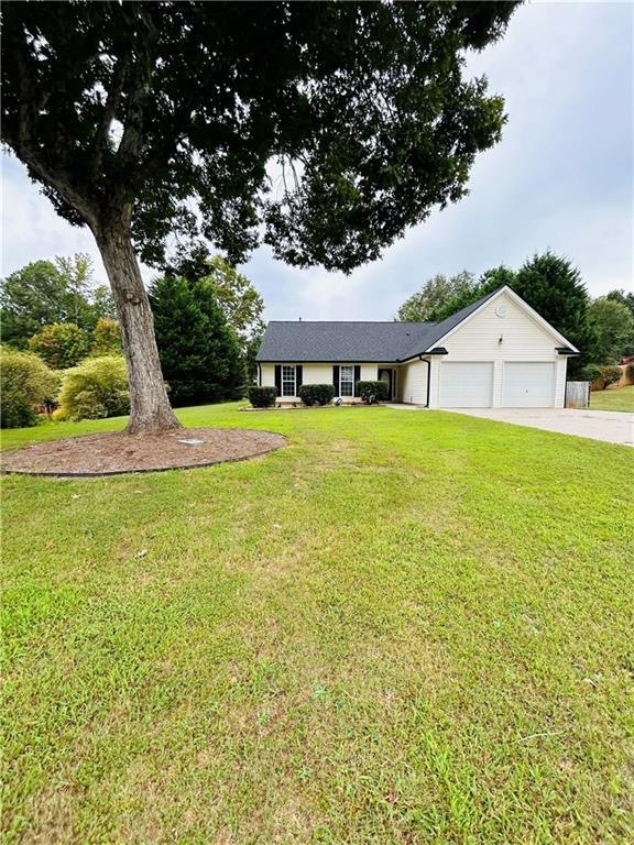 Single story home featuring a front yard and a gar