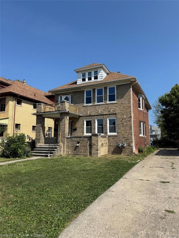 American foursquare style home with a balcony, brick siding, and a front yard
