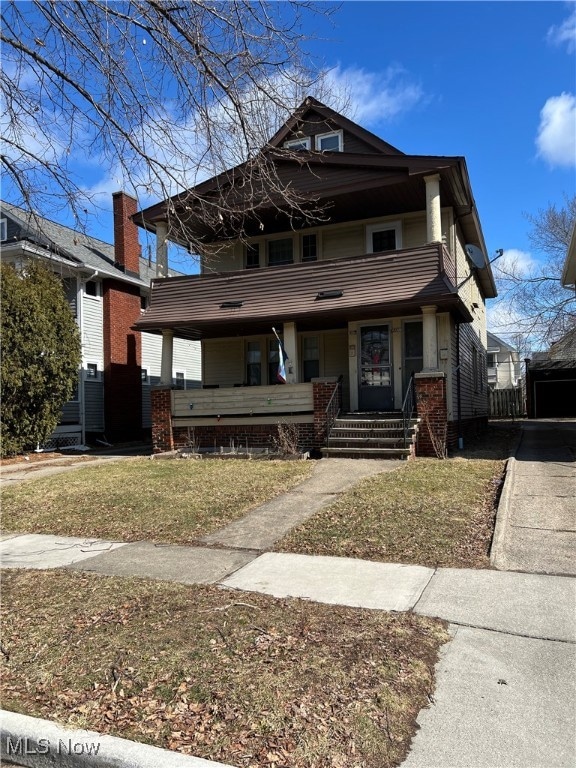 View of front of house featuring a porch, a front lawn, and a balcony