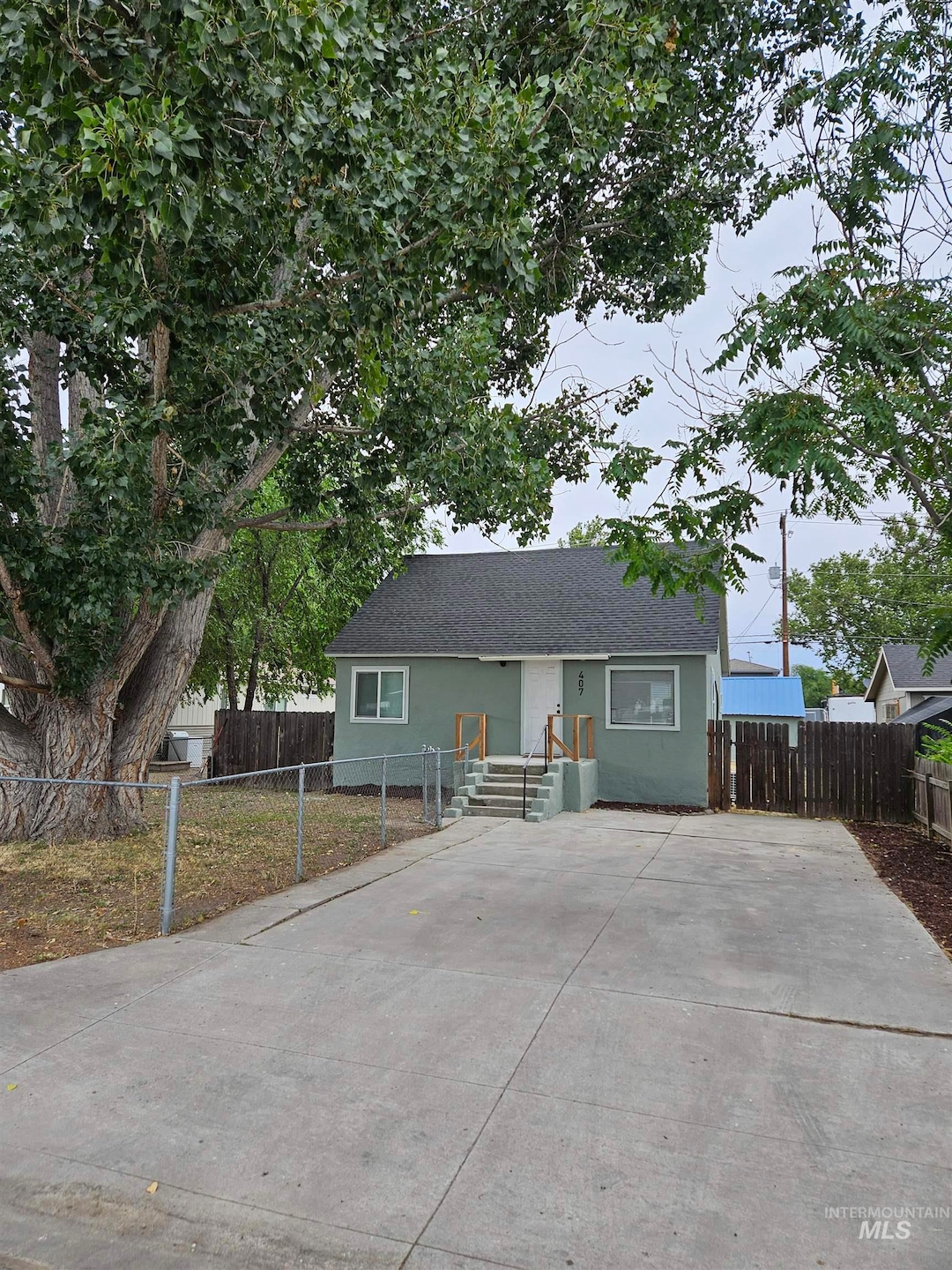 View of front of home with a shingled roof, stucco siding, and driveway
