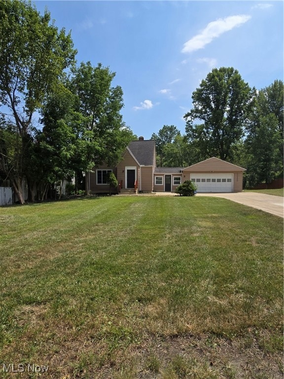 View of front of property featuring concrete driveway, a front yard, an attached garage, and a chimney