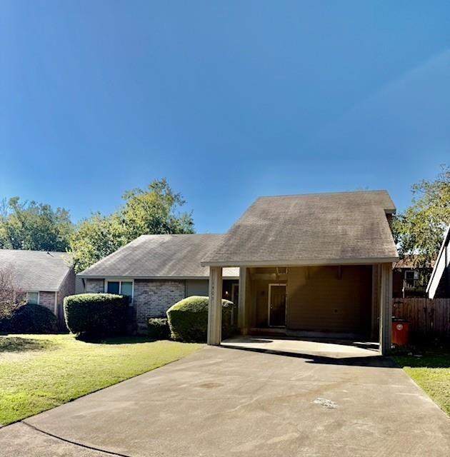 View of front of property with a shingled roof, an attached carport, and a front yard