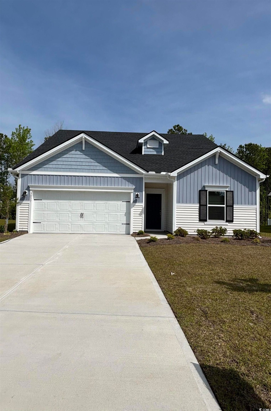 View of front of house featuring driveway, an attached garage, board and batten siding, and a front lawn