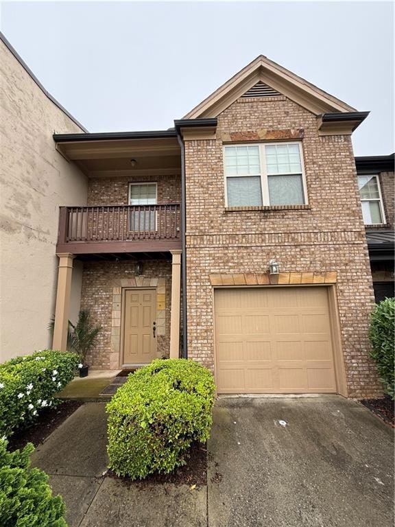 Traditional home with a balcony, brick siding, driveway, and a garage