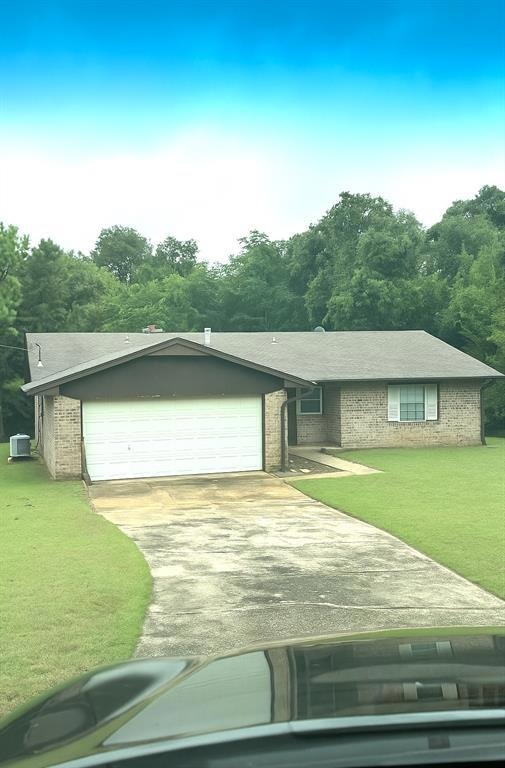 Ranch-style house featuring a front yard, concrete driveway, an attached garage, brick siding, and a shingled roof
