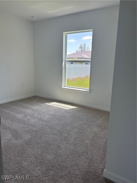 Empty room with carpet floors, baseboards, and a s