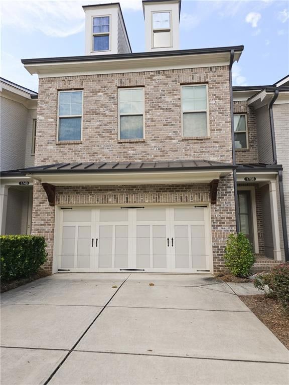 View of front of home featuring brick siding, driveway, and a garage