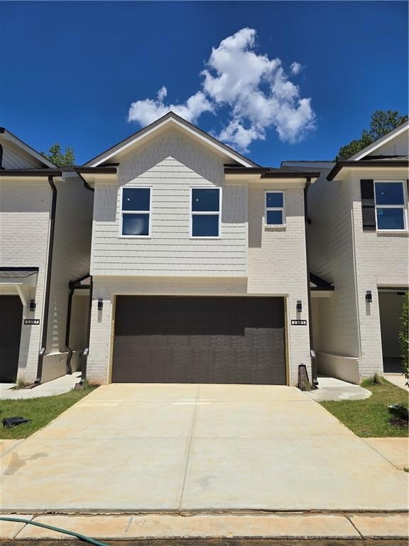 View of front of home with an attached garage, driveway, and brick siding