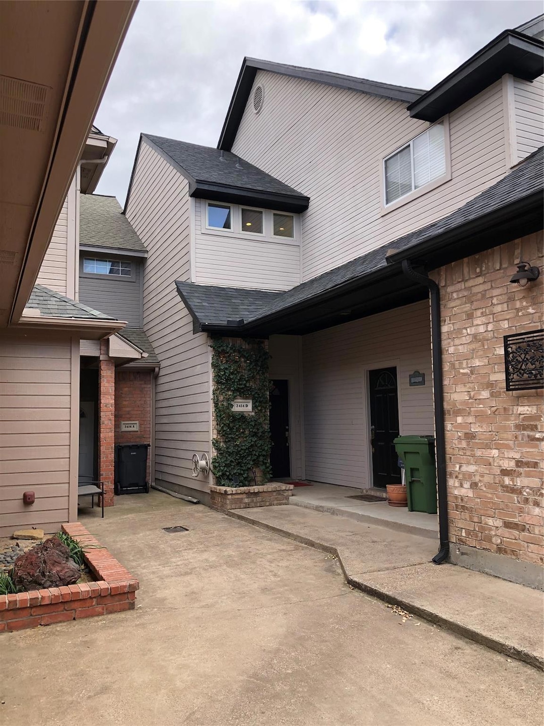 Front view of house featuring a patio, brick sidin