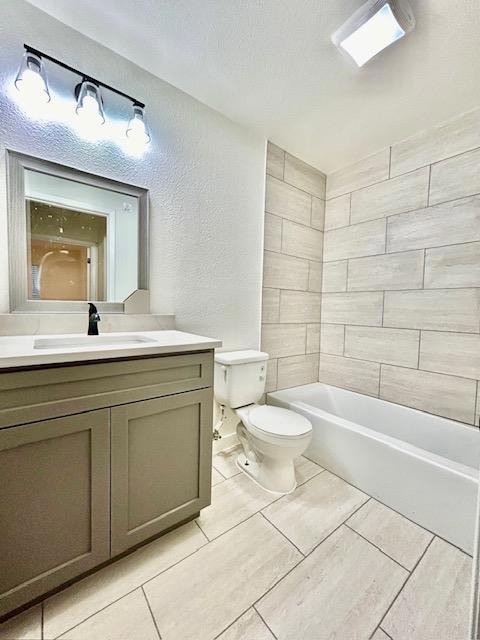 Full bath featuring toilet, vanity, a textured wa