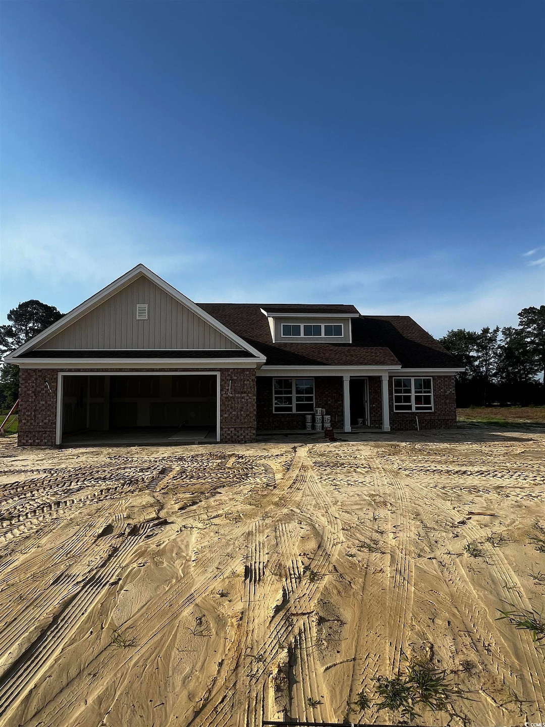 View of front facade with brick siding, an attached garage, and dirt driveway