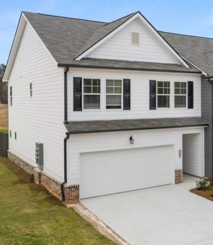 Traditional home featuring an attached garage, driveway, roof with shingles, and a front yard