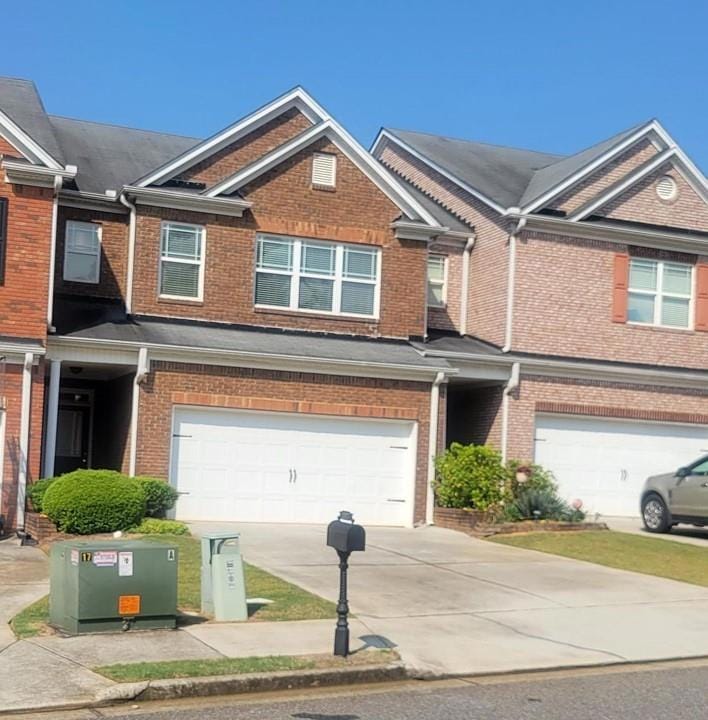 Townhome / multi-family property featuring an attached garage, brick siding, and concrete driveway