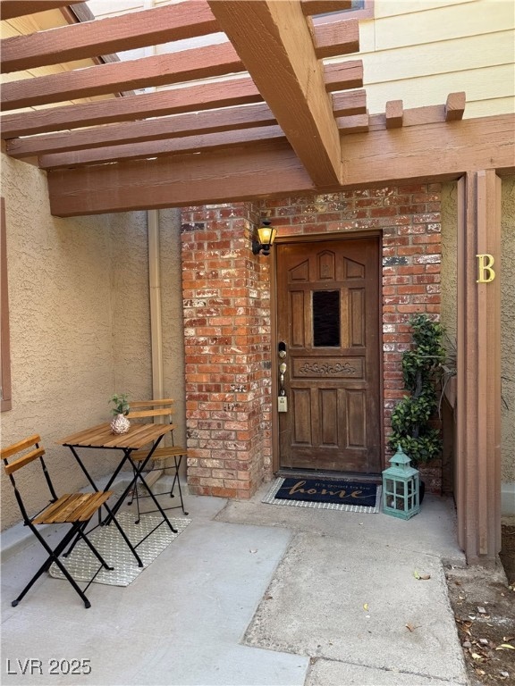 Property entrance featuring a pergola and brick si