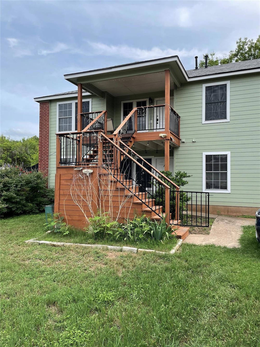 Rear view of house featuring a lawn and stairway