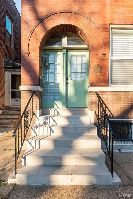 Doorway to property featuring brick siding