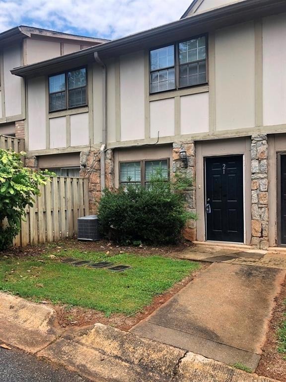View of front of property with stone siding, stucco siding, and cooling unit