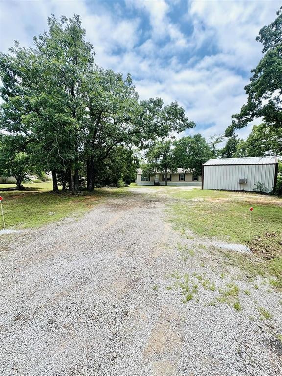 View of green lawn with a pole building and an outbuilding