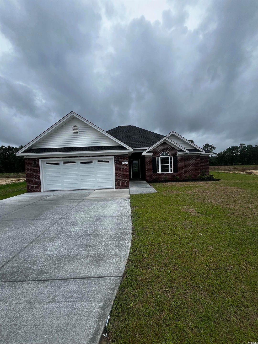 Ranch-style home with driveway, brick siding, a ga