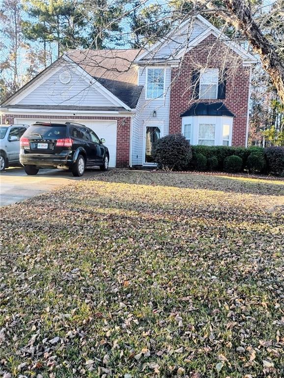 Traditional-style home featuring brick siding, an attached garage, and driveway