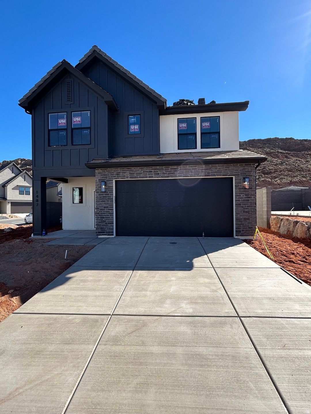 View of front of home with an attached garage, stone siding, and concrete driveway